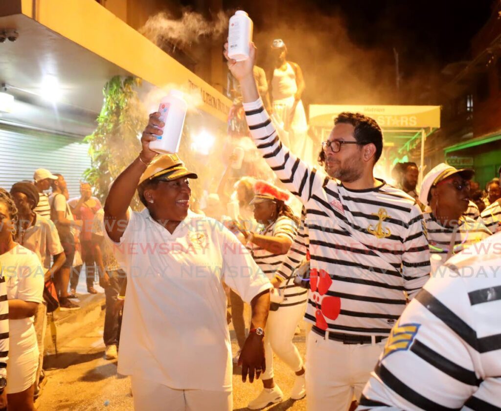 La Ministra de Planificación y Desarrollo, Penélope Beckles (izquierda), y el Ministro de Turismo, Randall Mitchell, disfrutan del desfile de cacerolas y pólvora en Pembroke Street en Puerto España el 21 de agosto.