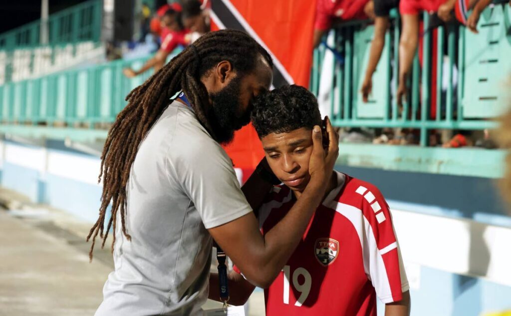 Distraught TT midfielder Sebastian James is consoled by assistant coach Yohance Marshall following the host's loss to French Guiana in the CFU Under-14 Boys' Challenge Series tier one semifinal at the Dwight Yorke Stadium, Bacolet, Tobago on August 23. - Photo courtesy TTFA