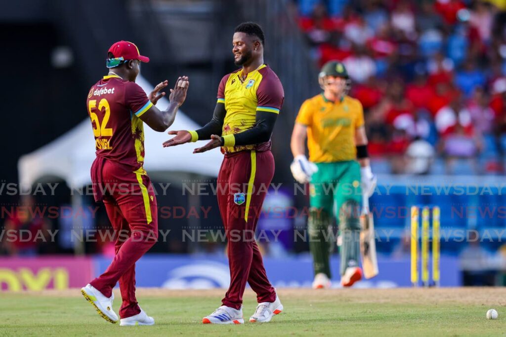 West Indies captain Rovman Powell, left, congratulates pacer Romario Shepherd after he took a wicket against South Africa in the second T20 at Brian Lara Stadium, Tarouba on August 25. - Photo by Daniel Prentice