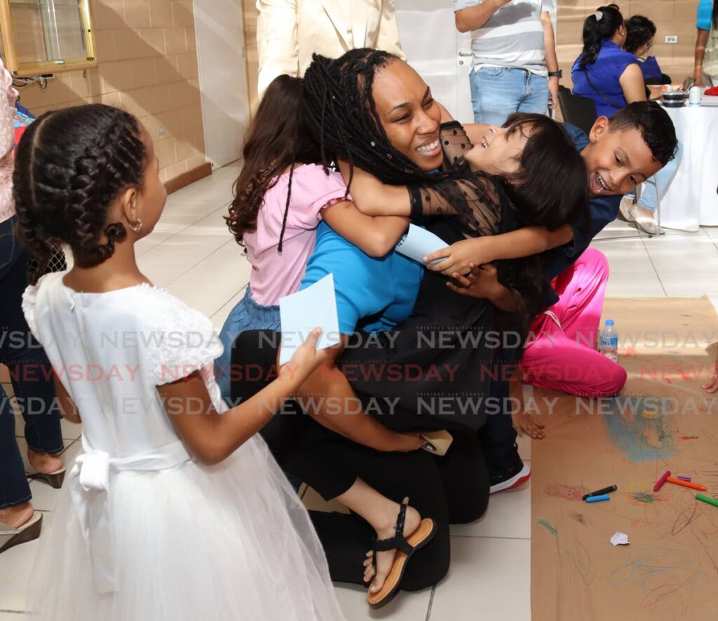 UNICEF education officer Tracey Lucas is hugged by migrant students at a UNHCR education-kits distribution cermony at NALIS, Port of Spain, on August 30. - Photo by Gabriel Williams