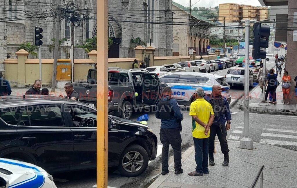 Officers speak to Opposition MP Rudranath Indarsingh after police intercepted bandits who stole a van at the corner of Park and Henry Street in Port of Spain on August 15. - Photo by Joey Bartlett