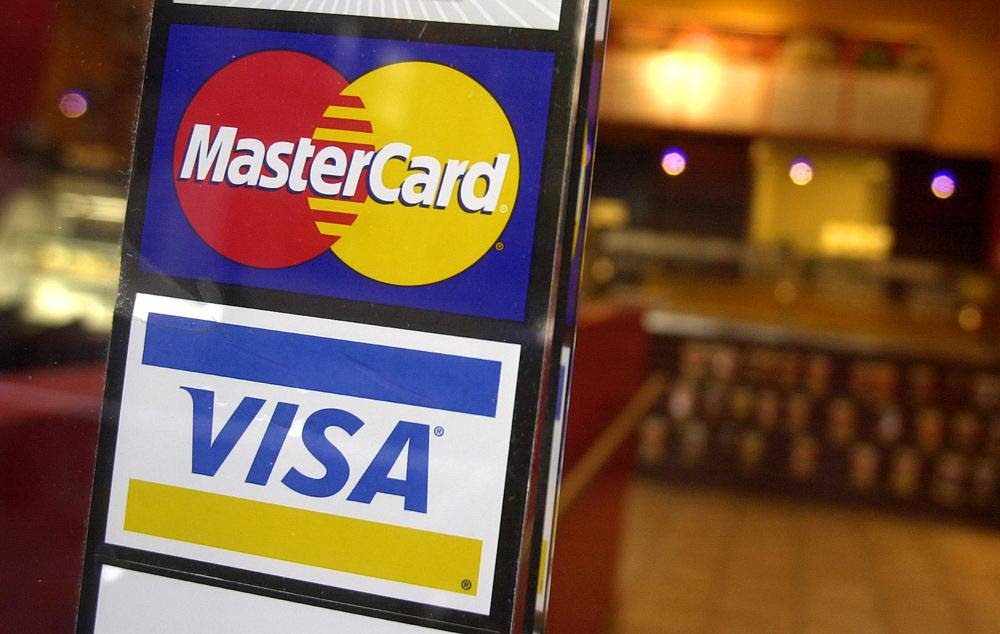 A small business has the logos for MasterCard and Visa credit cards at its entrance, letting customers know they accept credit card payments. -