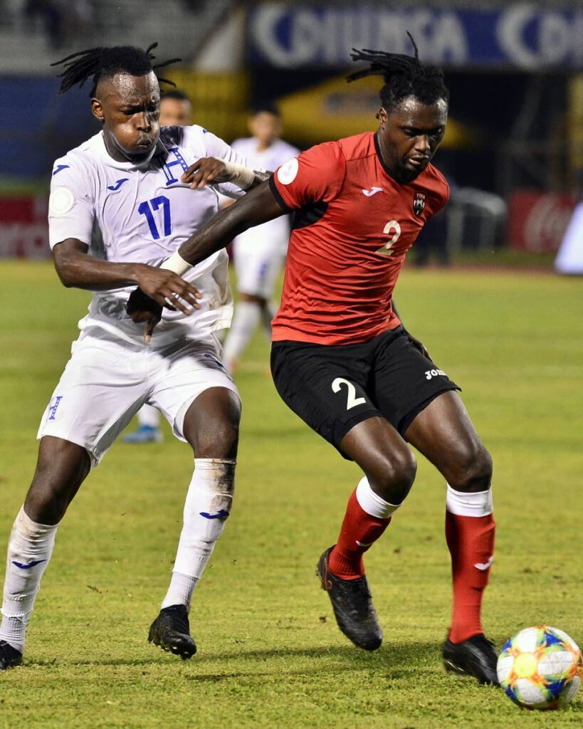 In this file photo, Alberth Elis (L) of Honduras and David Aubrey (R) of Trinidad and Tobago vie for the ball during a Concacaf National League match at Olimpico Metropolitano stadium in San Pedro Sula, Honduras on November 17, 2019.  - 