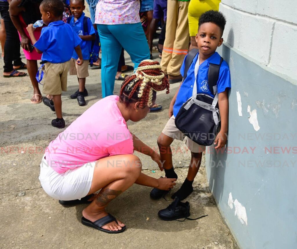 Shanalla Wright ties the laces of her son Liam Alfred, a student of Scarborough Methodist Primary School, on the first day of the school year on September 2. - Photo by Visual Styles