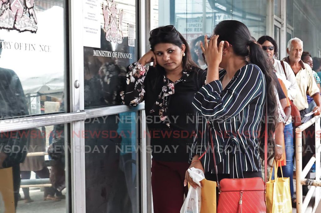 Customer's face shows her frustration as she waits in a long line outside the Board of Inland Revenue on Cipero Street in San Fernando as people rush to pay property tax on September 9. One woman at the back of the line said that she has been waiting for her turn for at least half hour. - Photo by Venessa Mohammed