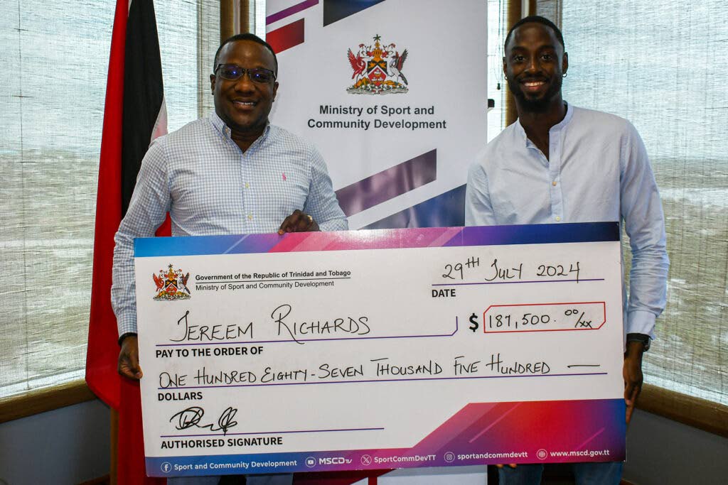 TT Olympian Jereem Richards, right, receives a cheque from acting permanent secretary of the Ministry of Sport and Community Development David Roberts at the ministry's head office in Port of Spain. - Photo courtesy Ministry of Sport and Community Development
