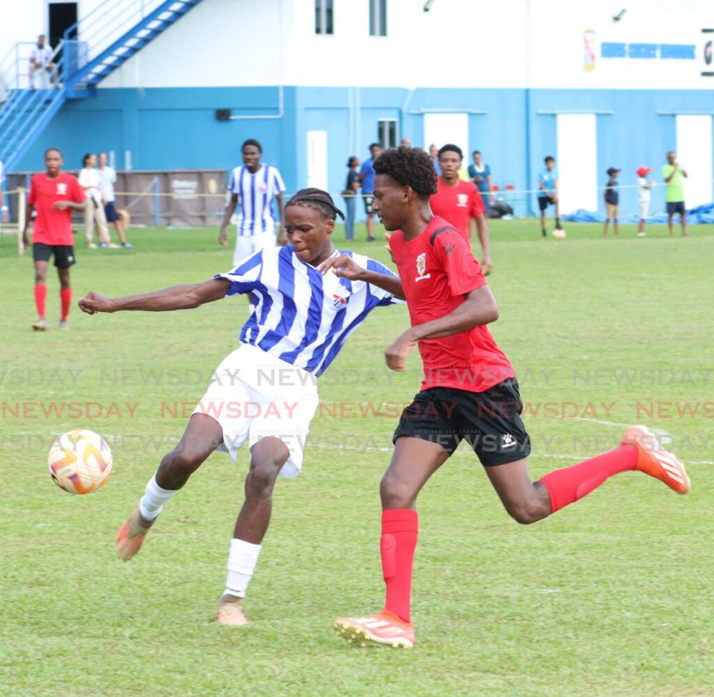 Isaiah Morris of St Mary's College, left, clears the ball out the box  as Terique Theobald of St Anthony's College tries to intercept during their SSFL premiership division match at St Mary's College Grounds earlier this season. Photo by Angelo Marcelle. - Angelo Marcelle