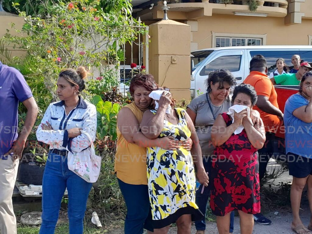 Darlene Bisnath, centre, mother of Angela Ali who died in a house fire in Cunupia, cries and is comforted by a relative as her daughter's body is taken away by undertakers on September 13. - File photo by Gregory Mc Burnie