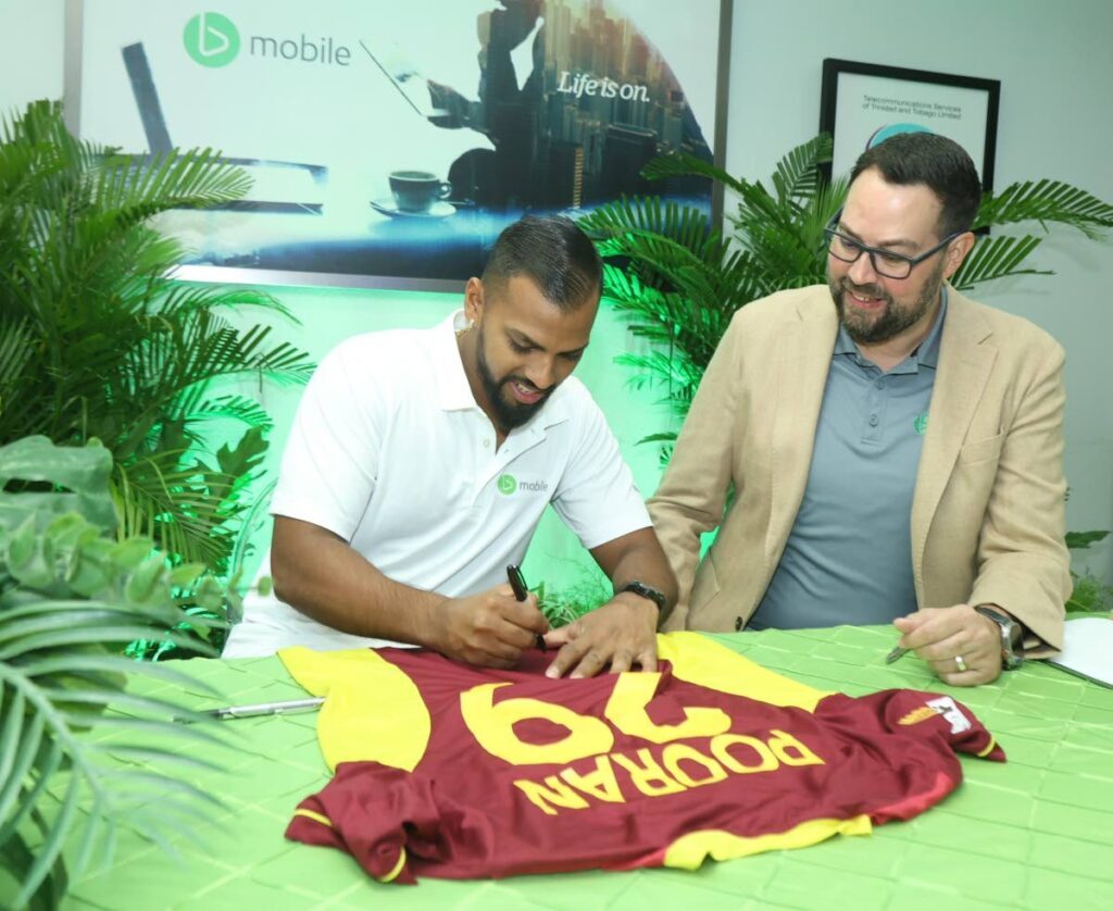 TSTT acting CEO Kent Western, right, looks on as star cricketer Nicholas Pooran signs a West Indies jersey after joining the bmobile family as a brand ambassador, at the TSTT booth, Queen's Park Oval, St Clair, earlier this month. - 