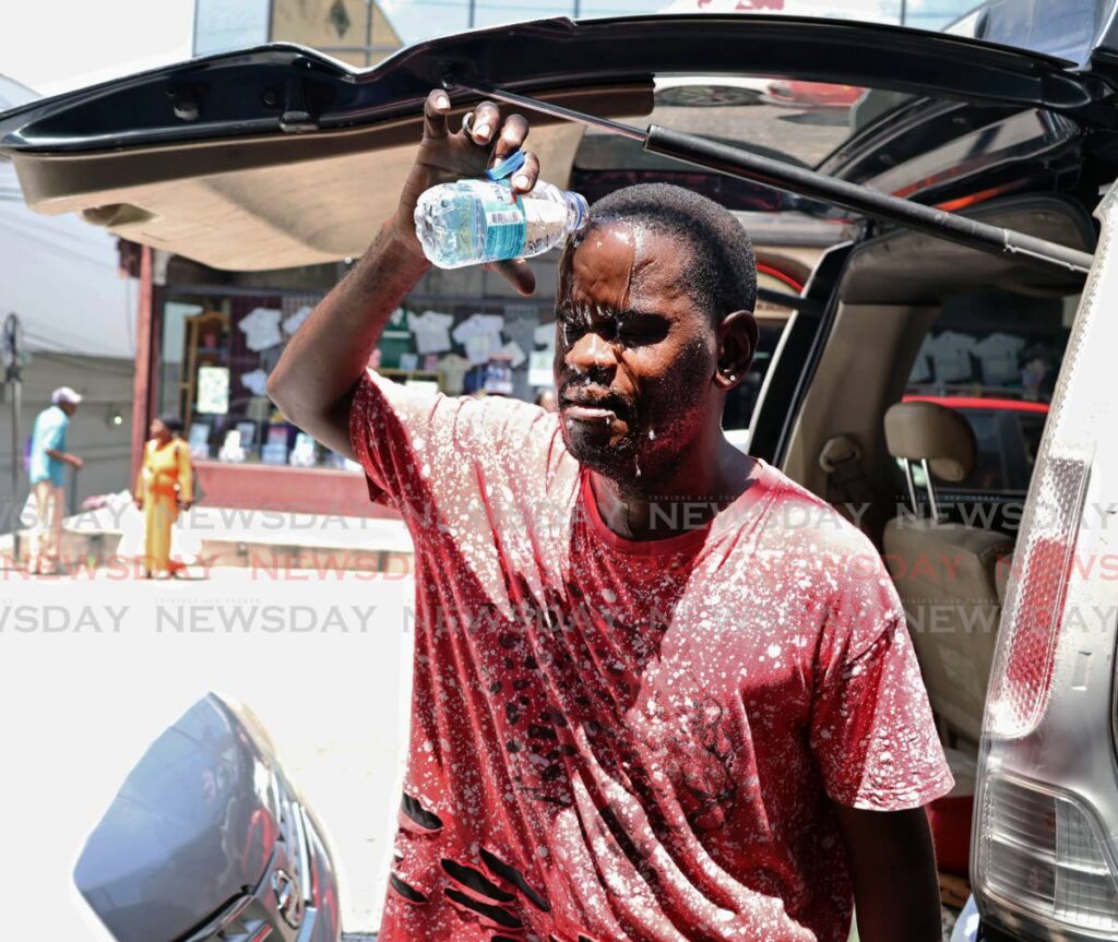 SEPTEMBER BLAZE: David also known as 'Swizzle Stickman,' pours a bottle of cold water on his face to cool down from the midday heat on High Street in San Fernando on September 17. The TT Meterological Service (TTMS) stated that there will be excessive heat in the month of September - Photo by Venessa Mohammed