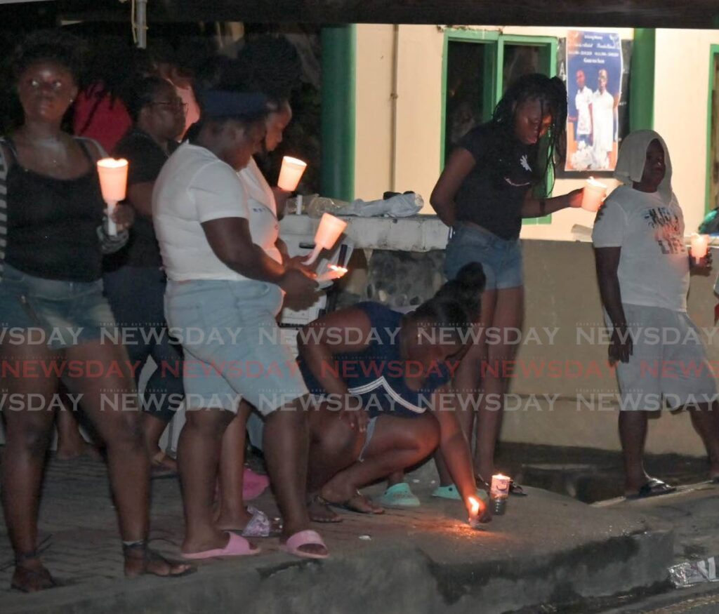 Residents of Argyle and Roxborough hold a candlelight vigil near Lammy Road, Argyle on September 24 following the murders of two Argyle men last weekend. - Visual Styles