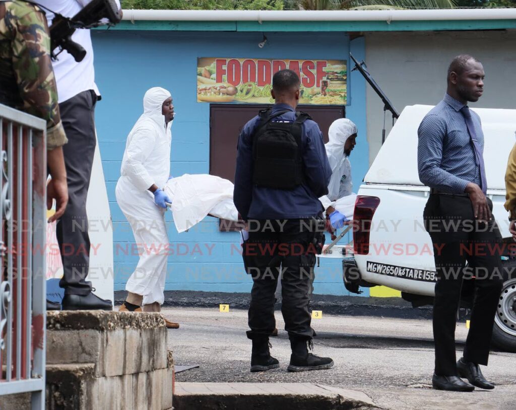 Crime Scene Investigators remove the body of Gerald Caliste, who was killed by gunmen outside of Roxann's Learning and Childhood Centre, Malick, around 8.10 am on September 25. - Photo by Faith Ayoung