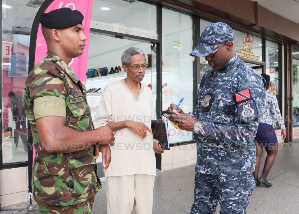 JOINT PATROL: Deputy Commissioner of Police (Operations) Junior Benjamin, right, and TTDF member Major Steve Benny, left, interact with National Joint Action Committee (NJAC) deputy political leader Embau Moheni during a walkabout in Port of Spain on September 25. - Photo by Faith Ayoung