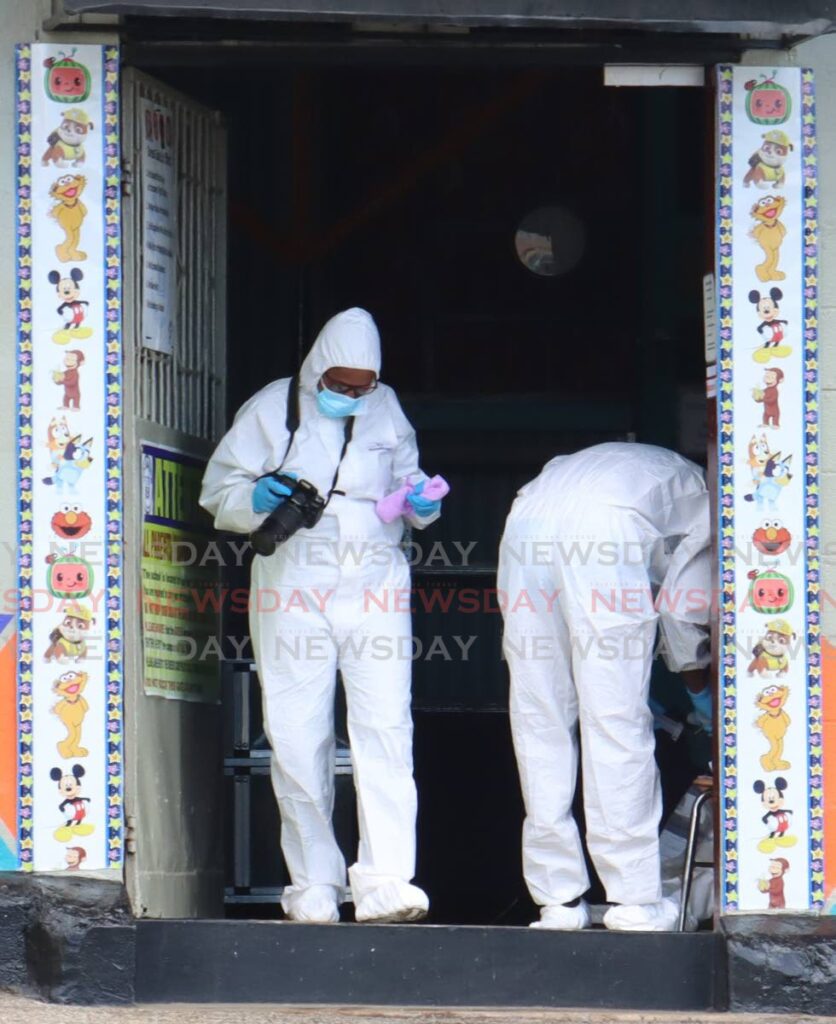 Crime scene investigators gather evidence at the entrance to Roxann’s Learning and Childhood Centre in Barataria, minutes after gunmen opened fire, killing two men and wounding three other people, including a four-year-old boy, on September 25. - Faith Ayoung