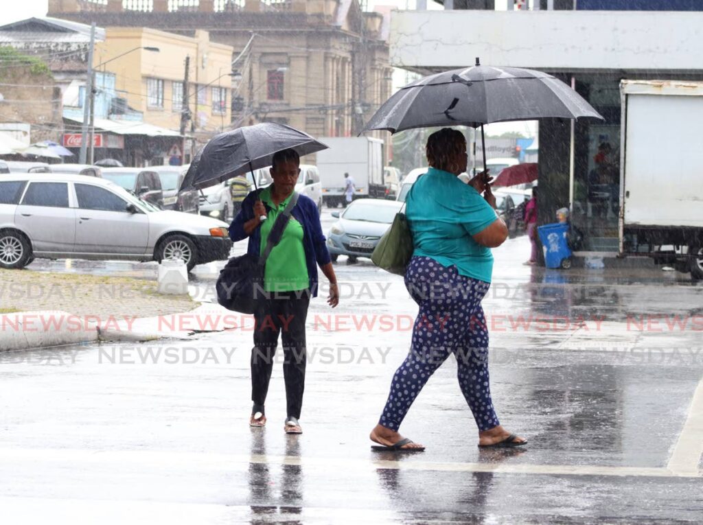 BLESSED SHOWERS: After a 5-day heat-spell, showers which fell in parts of Trinidad on Thursday would have been welcomed by WASA which has reported reservoirs at being well below average capacity for this time of the year. In this photo, two women walk along Independence Square in Port of Spain using umbrellas to shelter from the rain. PHOTO BY GABRIEL WILLIAMS  - Gabriel Williams