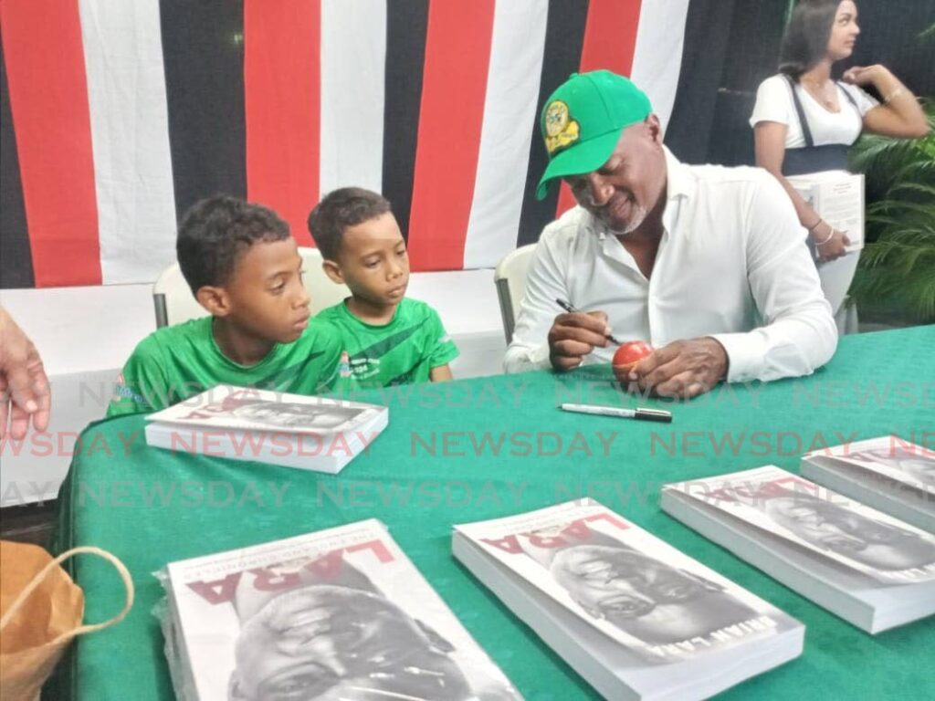 Brian Lara signs a ball for Harvard Club member Levi Pollidore, left, and his brother Ethan.   - Photo by Jelani Beckles