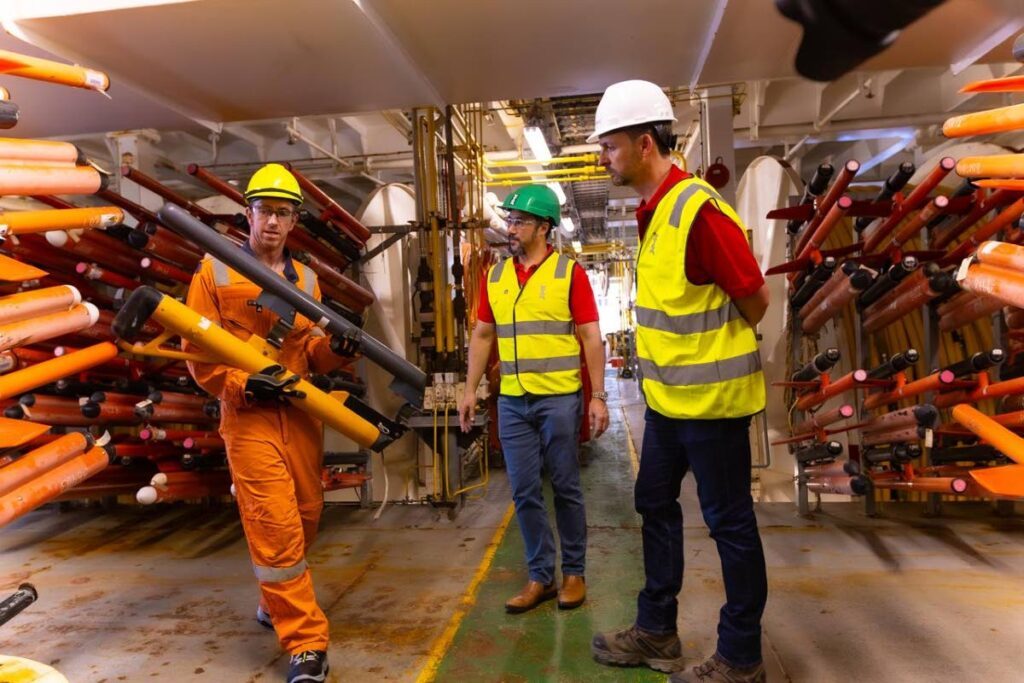 PXGEO 2 chief navigator Glen Stevens, left, describes the operation of a streamer depth control device to Energy Minister Stuart Young and Adam Lowmass, senior vice-president and country chair of Shell TT. - Photo courtesy MEEI