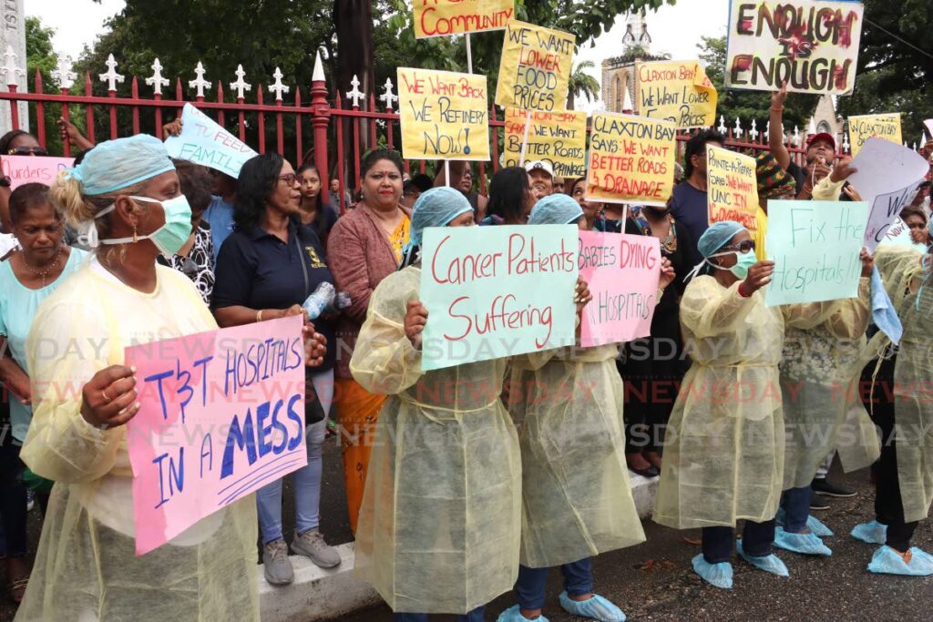 Protesters wearing surgical gowns hold signs about the state of the health sector and with a message that 