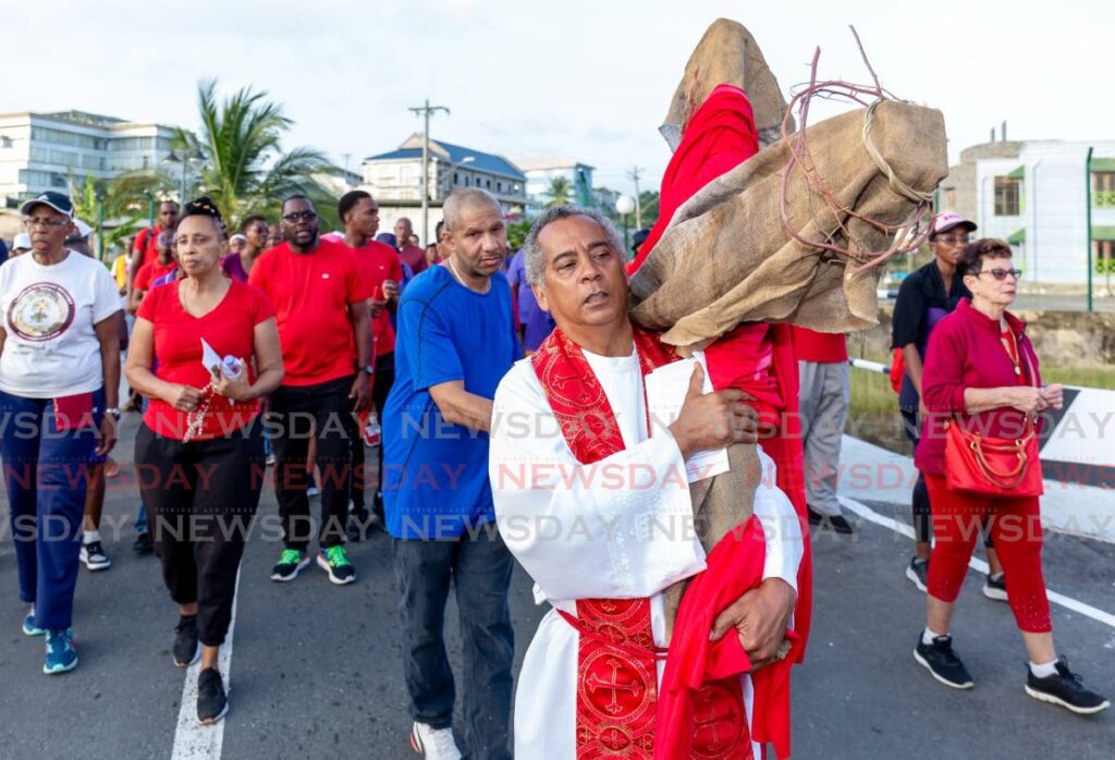 Fr Leslie Tang Kai, former parish priest, St Joseph Roman Catholic Church, Bacolet, Scarborough, Tobago carries a cross along the Smithfield Road, Scarborough, Tobago as part of the Way of the Cross in April 2023. - Photo by David Reid