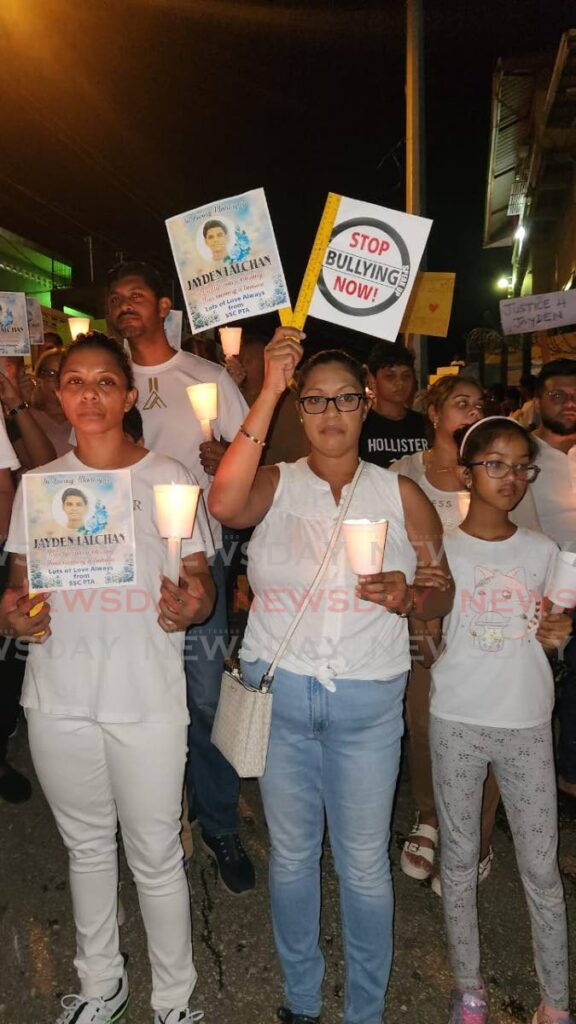 Fareeda Lalchan, left, and her sister Anjanee, centre, during a candlelight vigil on October 7 in Princes Town in memory of Lalchan's son Jayden, 15, who died by suicide on October 3, after enduring bullying at school. - Photo by Yvonne Webb 