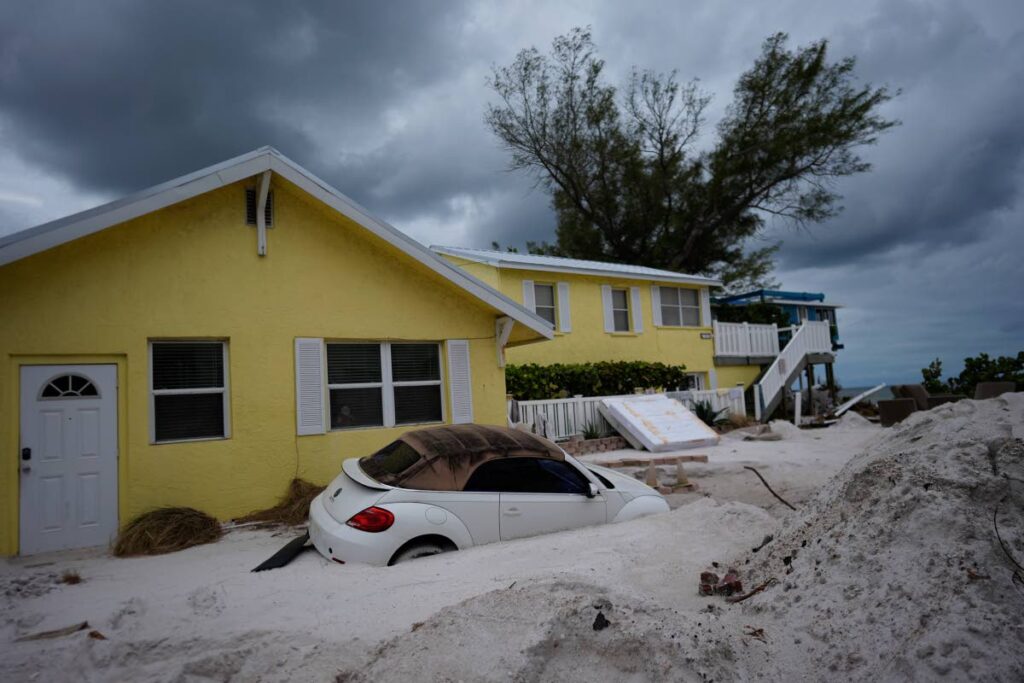 A car sits half-buried in sand as Bradenton Beach, Florida, which was in the process of cleaning up after Hurricane Helene, as Hurricane Milton approaches on Anna Maria Island, on October 8. AP PHOTO - 