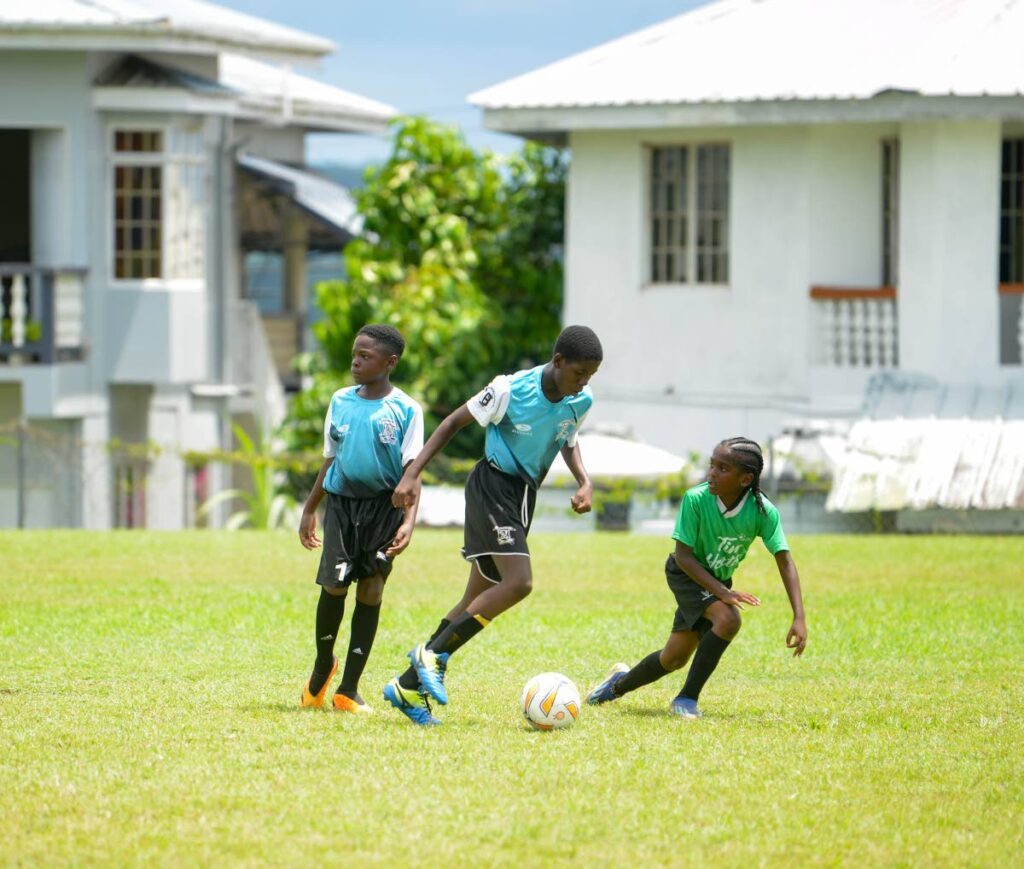 A Lambeau Anglican player, centre, takes on a Patience Hill Government player, right, during Tobago Primary Schools' Football League action at Signal Hill Recreation Ground on October 7. - Maurice Goddard