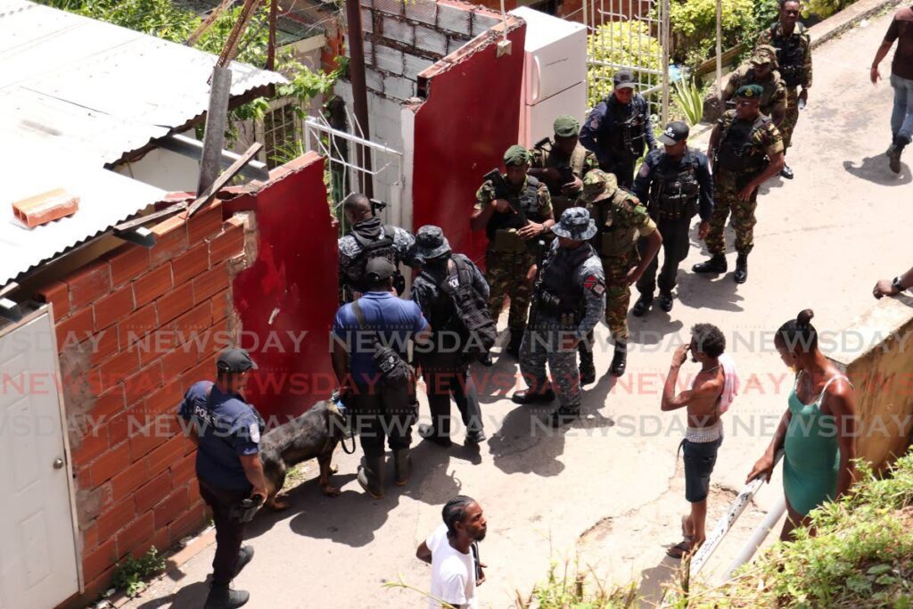 Police and soldiers prepare to enter the forest in search of the son of Anna Ellis who had been abducted by a male relative who earlier stabbed Ellis on Dibe Road, Long Circular Road, St James, on October 11. The boy was later found unharmed. - Photo by Faith Ayoung