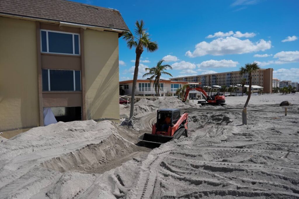 Scott Bennett, a contractor who specializes in storm recovery, drives a skid steer as he removes sand around 5-feet deep from the patio of a beachfront condominium in Venice, Fla., following the passage of Hurricane Milton on October 12. - AP Photo