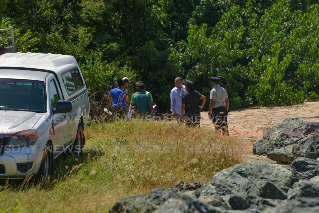 Police detectives, crime-scene investigators and undertakers at in conversation at the site at which Marcus Archer, 42, was found dead at a beach near the ANR Robinson International Airport in Crown Point, Tobago, on October 13. - Photo by Caswell Gordon