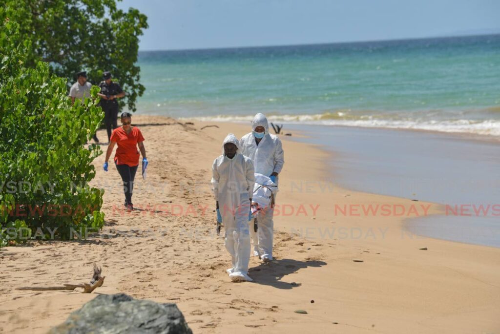 Undertakers remove a man's body found near the beach behind the ANR Robinson International Airport on October 13.  - Photo by Visual Styles