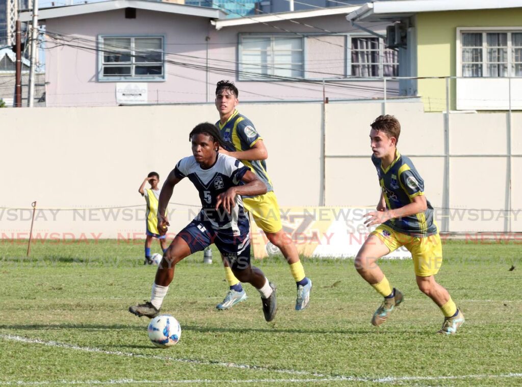 Trinity College East's Dexter Croal, left, runs with the ball against Fatima College in SSFL action at the Fatima Ground, Mucurapo on October 16. - Faith Ayoung