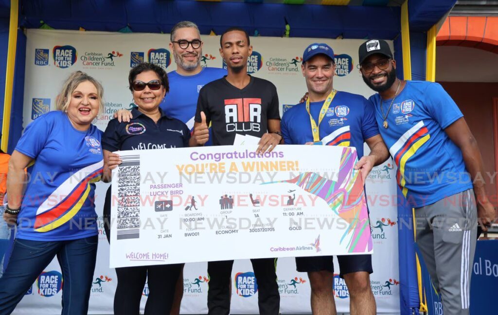 TT's Nicholas Romany, centre, collects his prize for winning the RBC Run for the Kids 15K on October 20 in Port of Spain. The prize was presented by Alicia Cabrera, CAL Marketing Loyalty Programmes executive manager, second from left, Marc Jardine, RBC managing director, third from left, and vice president and Chris Duggan, senior vice president and head RBC Caribbean Banking, second from right, flanked by actress Cecilia Salazar and comedian Rodell 