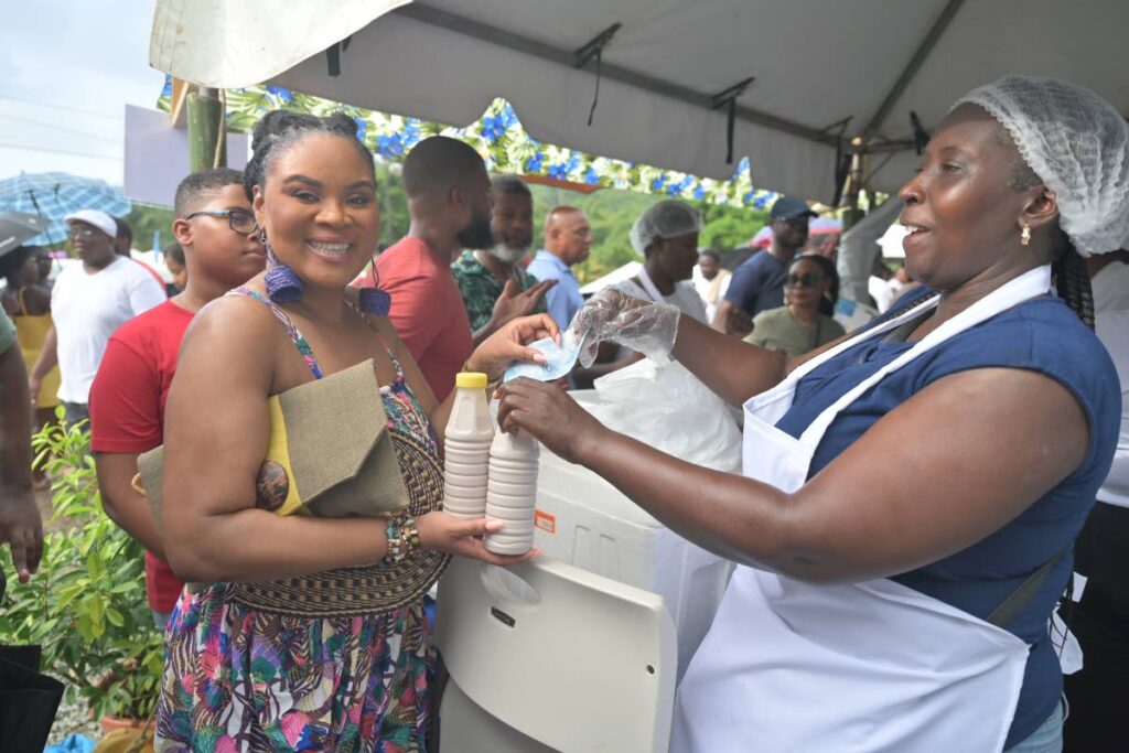 Minister of Sport and Community Development and Tobago West MP Shamfa Cudjoe, left, buys a dasheen punch from vendor Lystra George at the Blue Food Festival, at Mt Pleasant Recreation Ground, Tobago, October 20.  - Visual Styles 