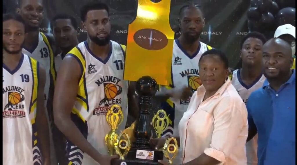 Maloney Pacers’ Tyrik Singh collects the team’s winning prize from Minister of Planning and Development and Arima MP Pennelope Beckles (2R) after their victory in the Anomaly Basketball final on October 20.  - 