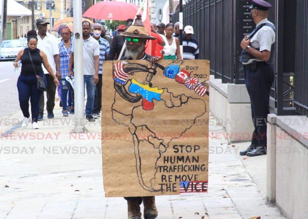 A man displays a placard during a march against human trafficking outside the Red House back in March 2023. FILE PHOTO - 