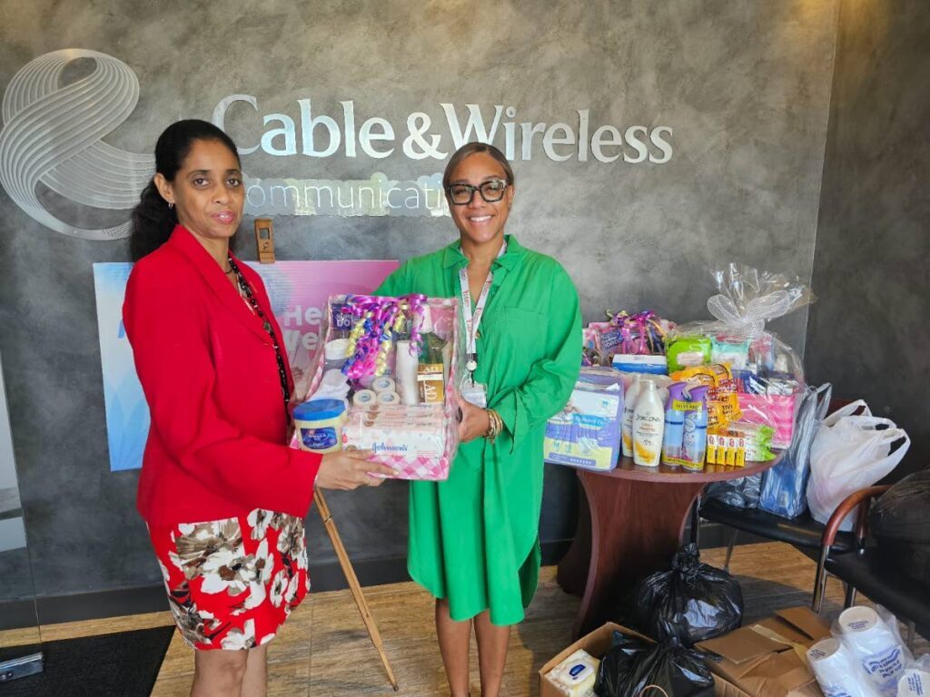 Flow vice president and general manager Simone Martin-Sulgan, right, presents one of the many hampers donated by staff to Gillian Baksh, secretary, Trinidad and Tobago Palliative Care Society. - Photos courtesy Flow