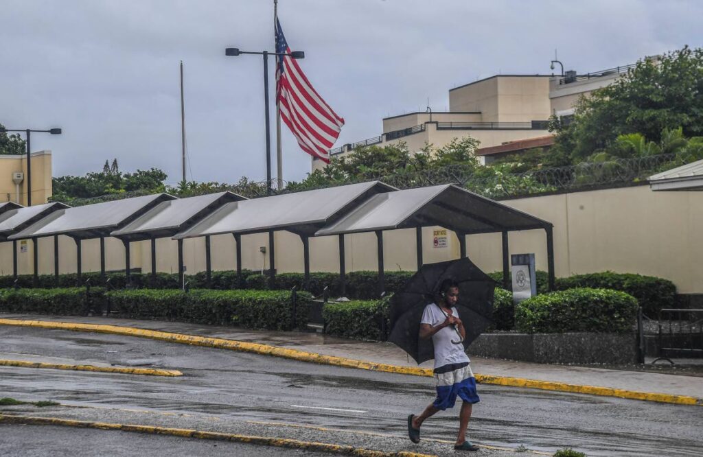 A man walks past the the US Embassy during rains brought on by tropical storm Rafael in Kingston, Jamaica on November 5. - AP PHOTO