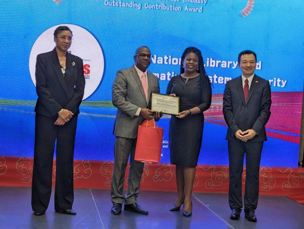 Permanent Secretary in the Ministry of Foreign and Caricom Reita Toussaint,  left, chairman of Nalis Neil Parsanlal, and Paula Greene, executive director, with the award presented by Chargé d’Affaires of the Chinese Embassy Yang Han. - 