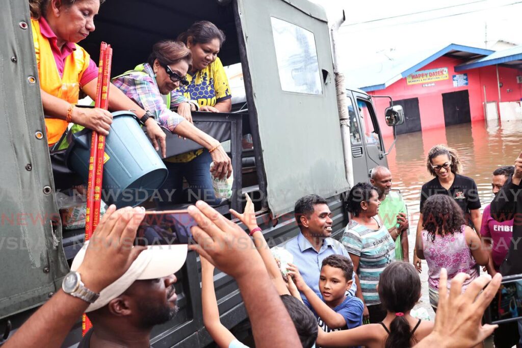 Opposition Leader Kamla Persad-Bissessar, centre, and councillor Shanti Boodram distribute cleaning supplies from the back of a TT Regiment truck Penal residents affected by extensive flooding on Lachoos Road, Penal, on November 13 - Photo by Lincoln Holder 