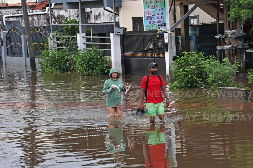 Two residents walk through a flooded Lachoos Road in Penal on November 13. - Photo by Lincoln Holder - Lincoln Holder 