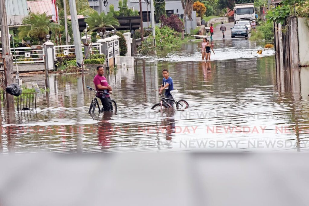 Residents wade through floodwaters on Lachoos Road, Penal on November 13. - Photo by Lincoln Holder