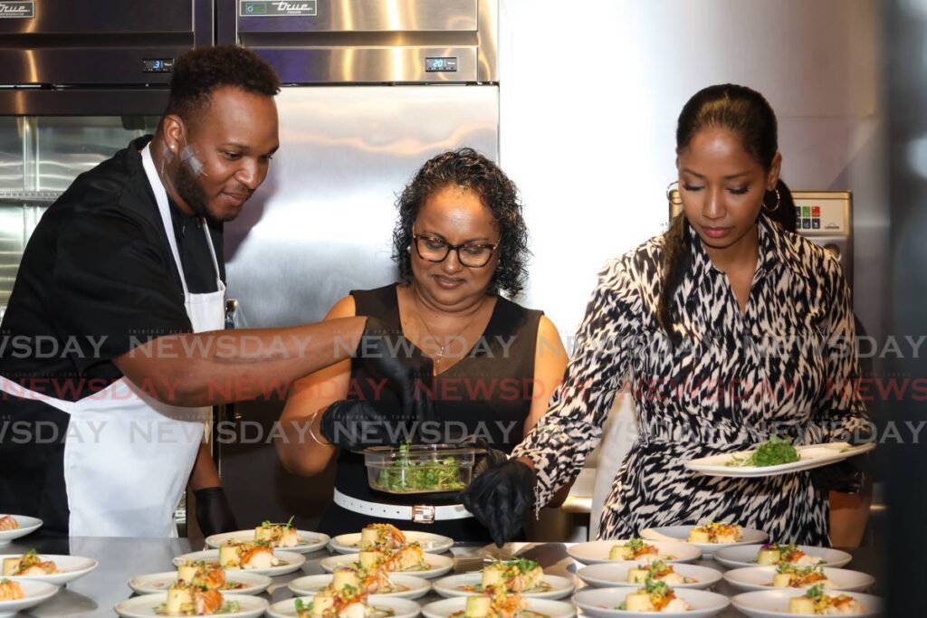 Chef Rondell Thompson, left, helps Donna Budhoo, strategic account manager at C&W Business and Eva Mitchell, CEO of TT Stock Exchange prepare multiple plates of a lobster and corn dish at C&W Business Plated networking event at The Forge, Chootoo Rd, El Socorro Ext, San Juan on November 15.  - Photo by Faith Ayoung