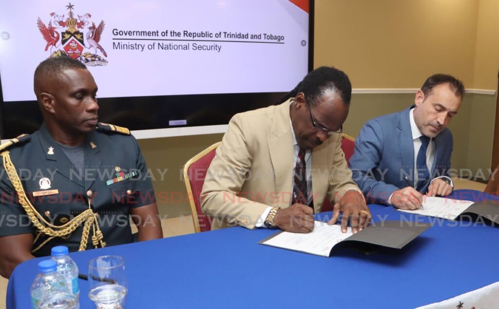 SIGN-OFF: National Security Minister Fitzgerald Hinds signs  documents relating to the donation of two drones by the UN's Office on Drugs and Crimes, at his ministry in Port of Spain on Wednesday. Looking on at left is CDS Darryl Daniel, and UNODC official Roberto Codesal, at right. PHOTO BY ANGELO MARCELLE - Angelo Marcelle