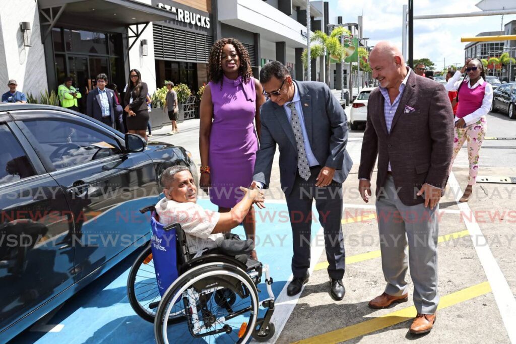 Sudhir Ramessar, who has spina bifida, shakes hands with Works and Transport Minister Rohan Sinanan at the launch of Persons with Disabilities Parking Permit Regulations on November 22 at South Park Mall, San Fernando. Looking on are Minister of Social Development and Family Services Donna Cox and Anthony Rahael, CEO of South Park Mall. - Photo by Lincoln Holder