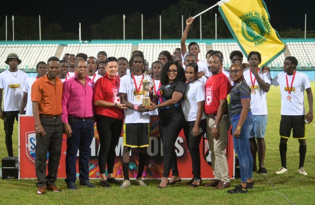 Signal Hill Secondary captain Kerron Arthur receives the trophy from Secretary of Education Zorisha Hackett. Other officials including SSFL president Merere Gonzales, second from left front row, also took part in the closing ceremony. - Photo courtesy Caswell Gordon