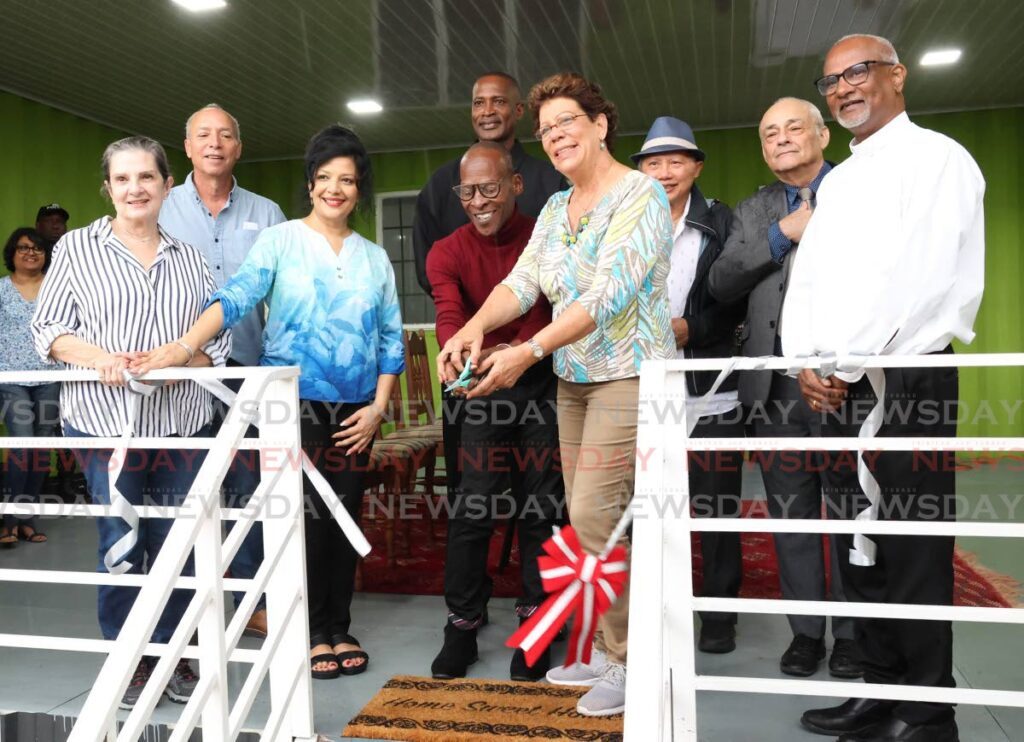 Children's Ark president Simone De La Bastide, centre,  cuts the ribbon with Wayne Jordan, for his new home at Beetham Gardens, Port of Spain on November 23.  - Photo by Faith Ayoung