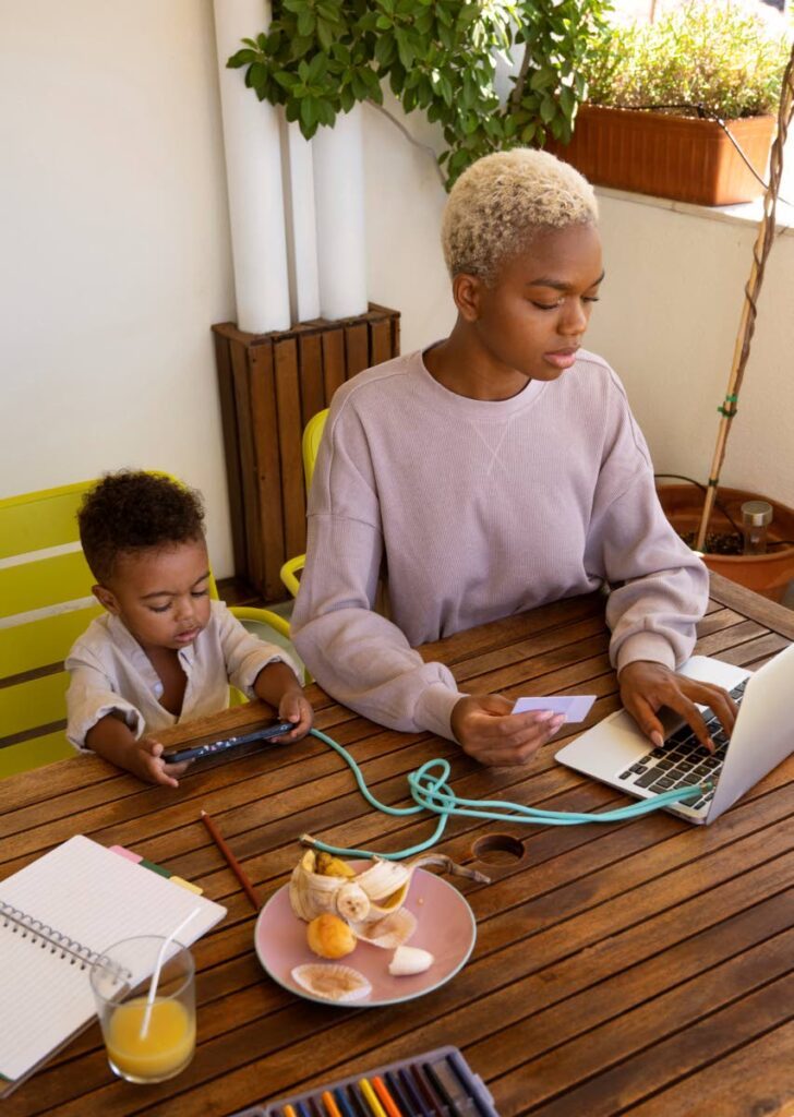 A woman works from home while her child sits next to her.  - Photo courtesy Freepik 