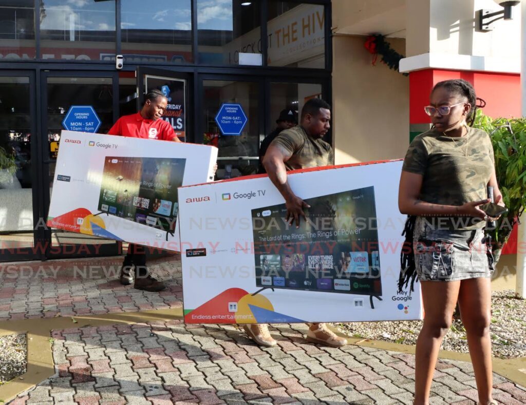 This customer gets assistance to carry his televisions during the Black Friday sale at Standards Distributors Limited, Grand Bazaar, on November 29. - Photo by Ayanna Kinsale 