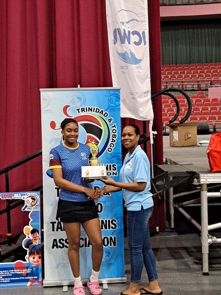 QPCC’s Imani Edwards-Taylor receives one of her two trophies after winning the women’s and girls’ U19 singles events at the Tobago Table Tennis Open. - Photo courtesy Tobago Table Tennis Open