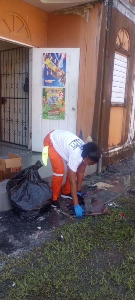 An employee of the Housing Development Corporation assists in clean-up operations after a fire at Building 17, Maloney Gardens early on December 7. - Photo courtesy HDC